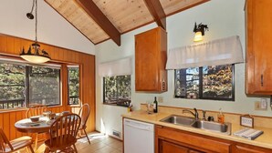Une cuisine dotée de meubles en bois, d’un lave-vaisselle, d’un évier et d’un coin repas avec des chaises et une table.