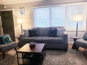 A living room with a grey sofa, two armchairs, a coffee table, and two lamps.
