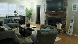 A living room with a fireplace, a sofa, a coffee table, and a TV.