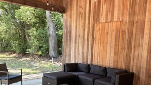 A covered outdoor seating area with a sectional sofa, wicker chairs, and a patterned rug.
