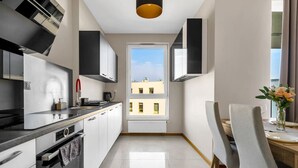 A modern kitchen with a window view, a dining area with a table and chairs, and a small vase with flowers.