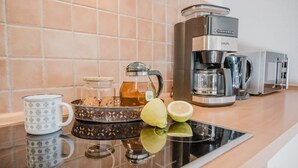 A kitchen with a coffee maker, a kettle, a mug, and a fruit bowl on the counter. - Vacation apartment half-timbered house "Westen oben" - Bauernhof Hopp (Fehmarn)