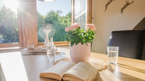 A wooden table with an open book, a vase with flowers, and glasses of water. - Vacation apartment half-timbered house "Westen oben" - Bauernhof Hopp (Fehmarn)