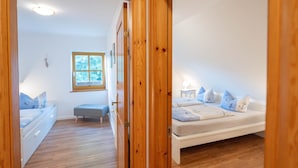 A bedroom with a bed, a bench, a window, and a door. - Vacation apartment half-timbered house "Westen oben" - Bauernhof Hopp (Fehmarn)