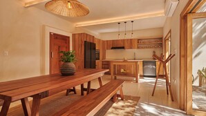 A modern kitchen with wooden cabinets, a dining table, and a hanging light fixture.