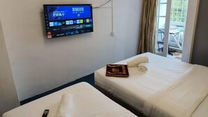A hotel room with two beds, a TV mounted on the wall displaying the UEFA Champions League, and a window with curtains. - cool memories hotel  (Tanah Rata)