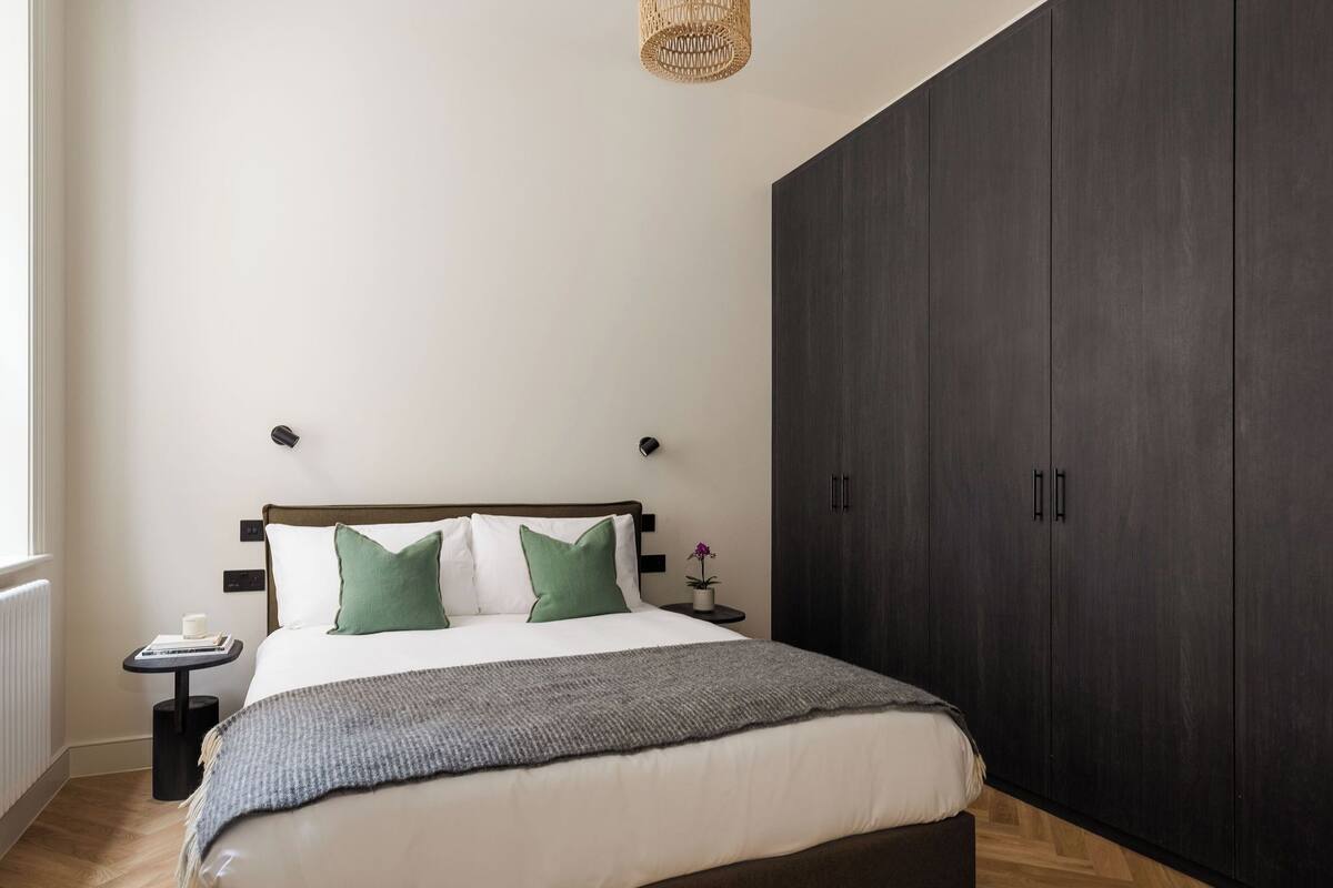 A bedroom with a bed, bedside tables, a wardrobe, and a window.