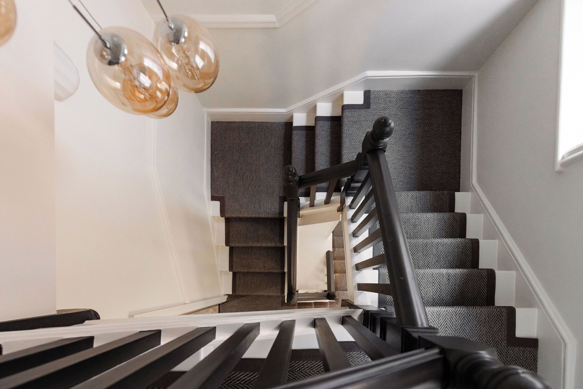 A staircase with a black handrail and patterned carpet.