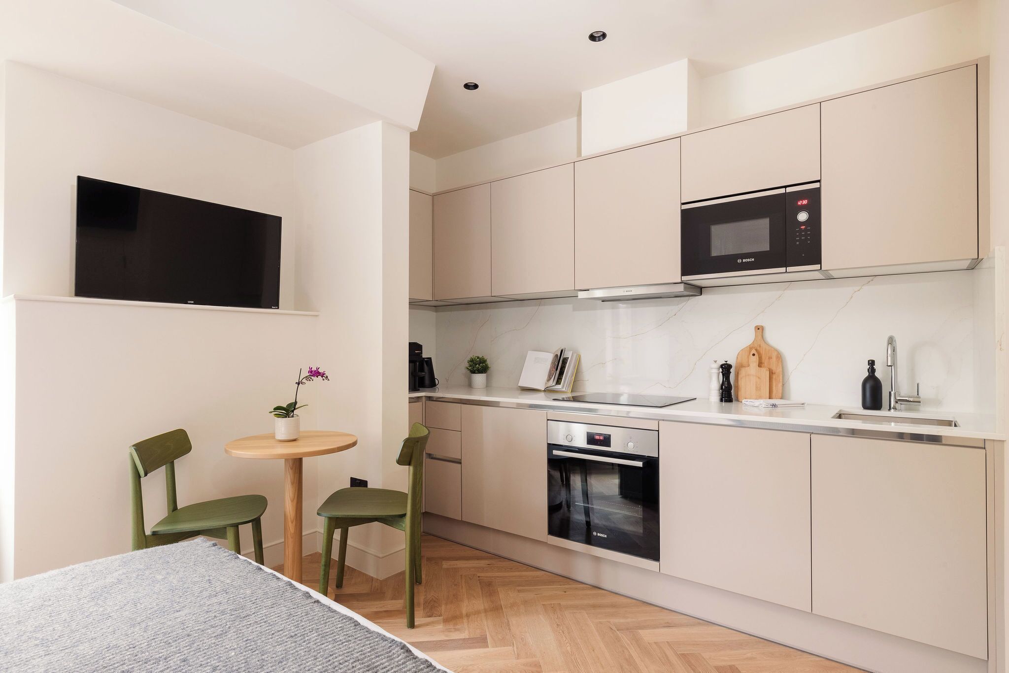 A compact kitchen with a microwave, oven, and a small dining area with two chairs and a table.