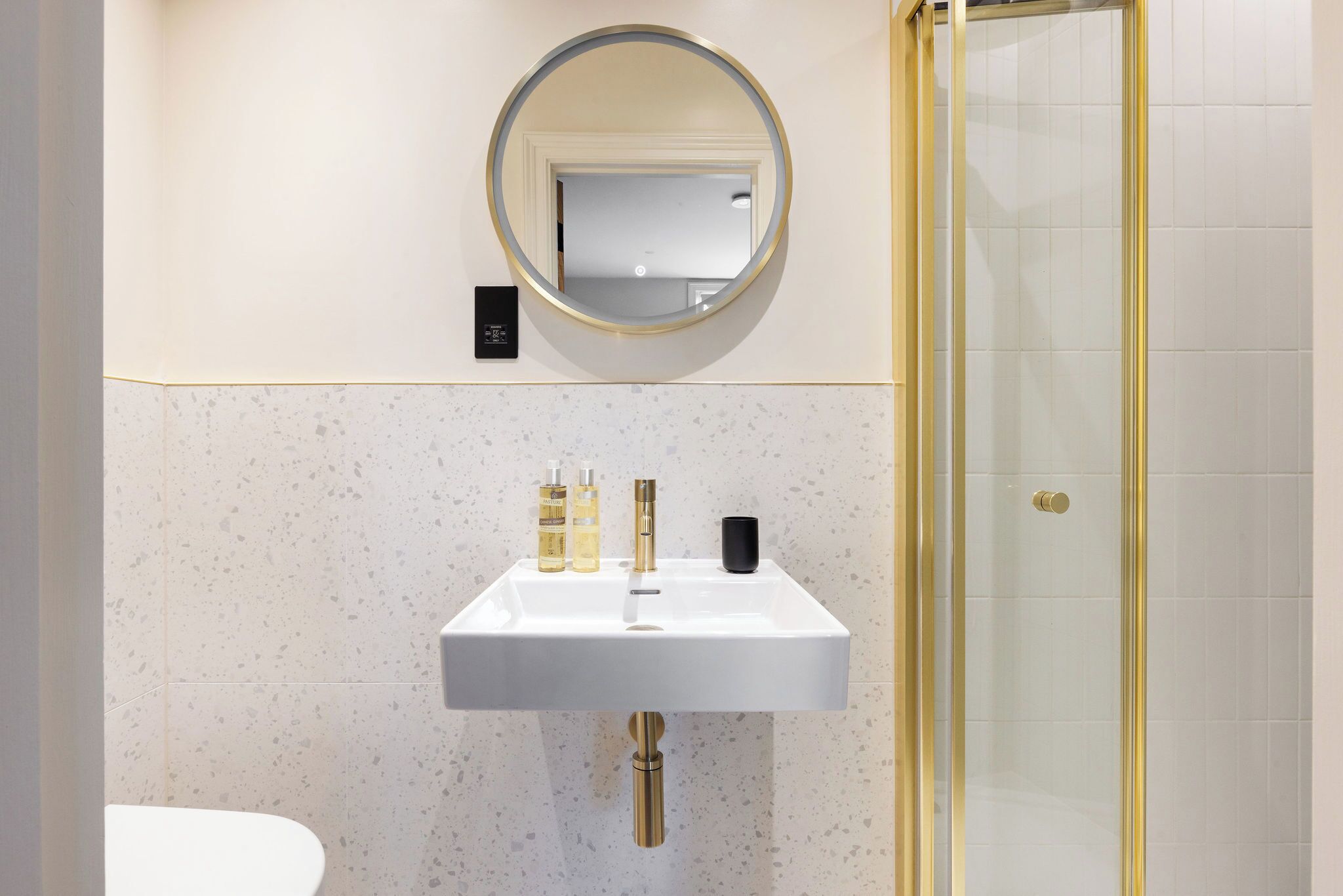 A bathroom with a white sink, a round mirror, and a glass shower enclosure.