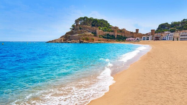 A beach with clear blue water, a sandy shore, and a historic castle on a hill. - Apartment in Tossa de Mar for 4 People (Tossa de Mar)