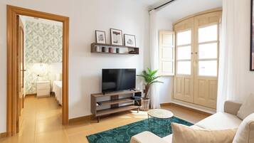 Ein Wohnzimmer mit Fernseher, Sofa und einem Teppich mit grünem Muster.