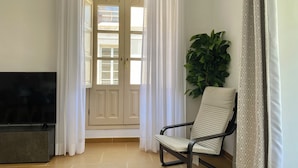 Una sala de estar con televisor, una silla y una planta.