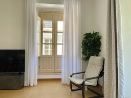 Un salon avec un téléviseur, un fauteuil et une plante.