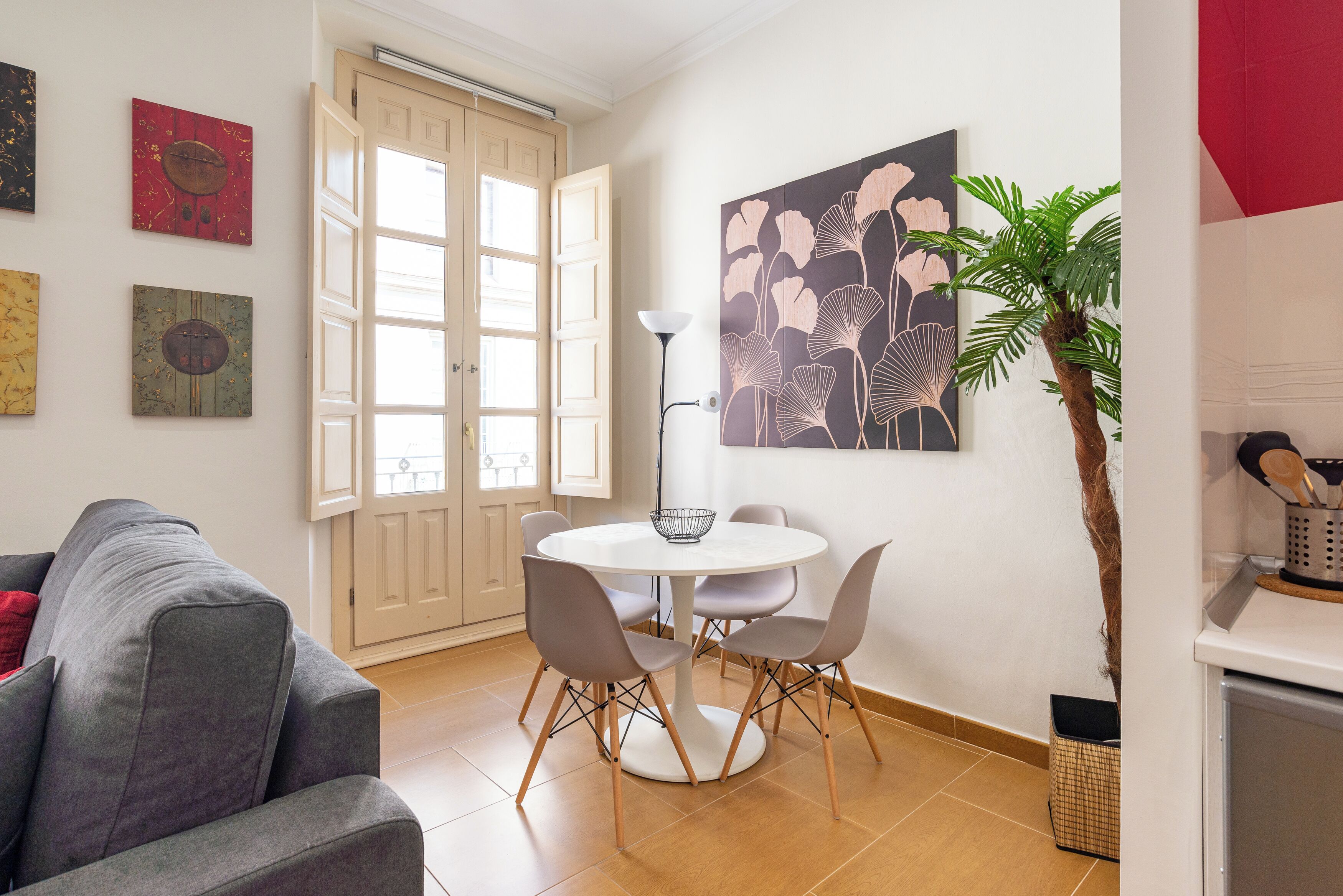 A dining area with a round table, four chairs, and a floor lamp.
