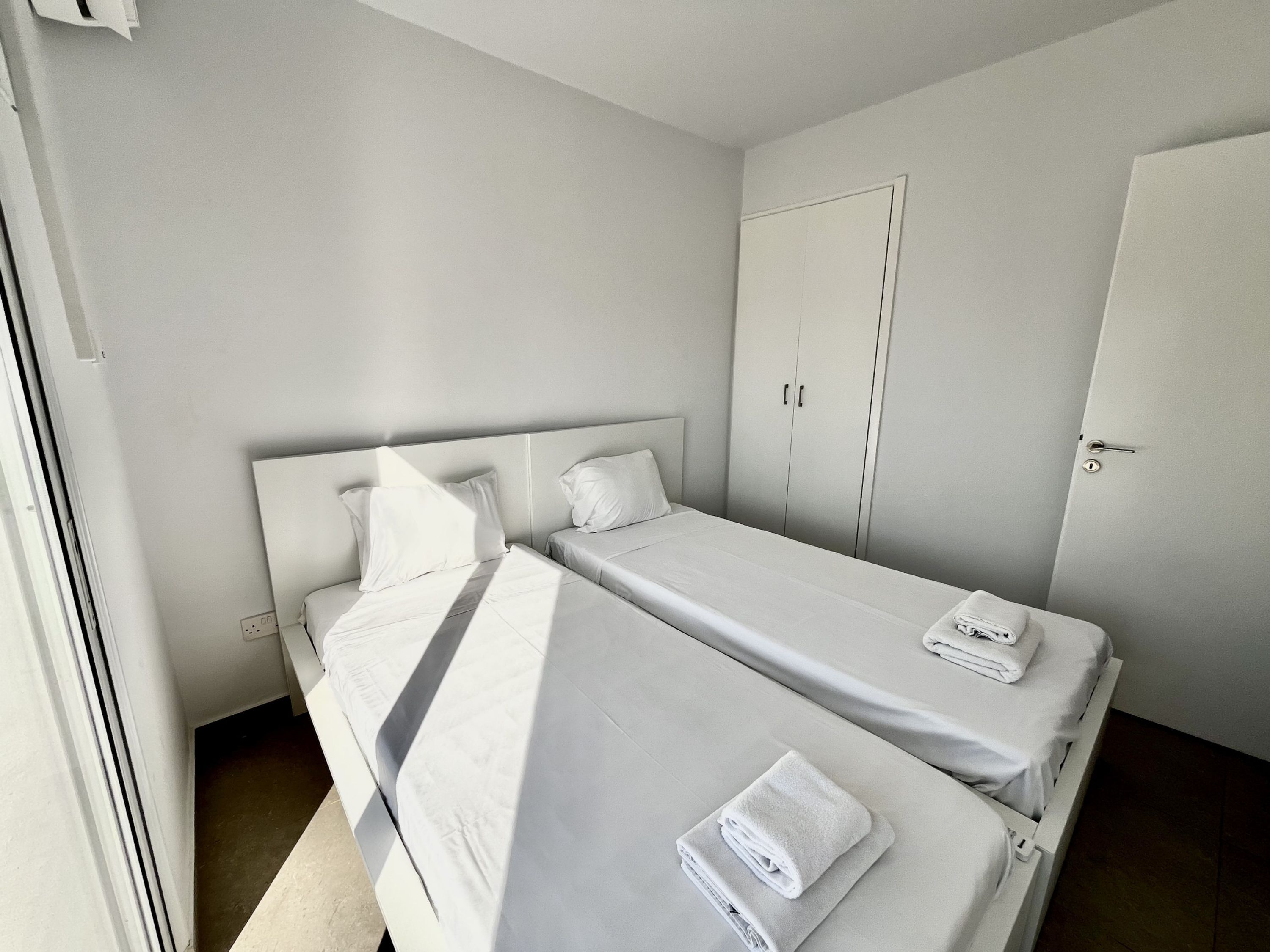 Habitación doble con dos camas, un armario y una puerta.