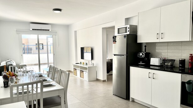 A modern kitchen with white cabinetry, a built-in microwave, and a refrigerator. - 04 AN - Stay Ease Apartment (Ayia Napa)