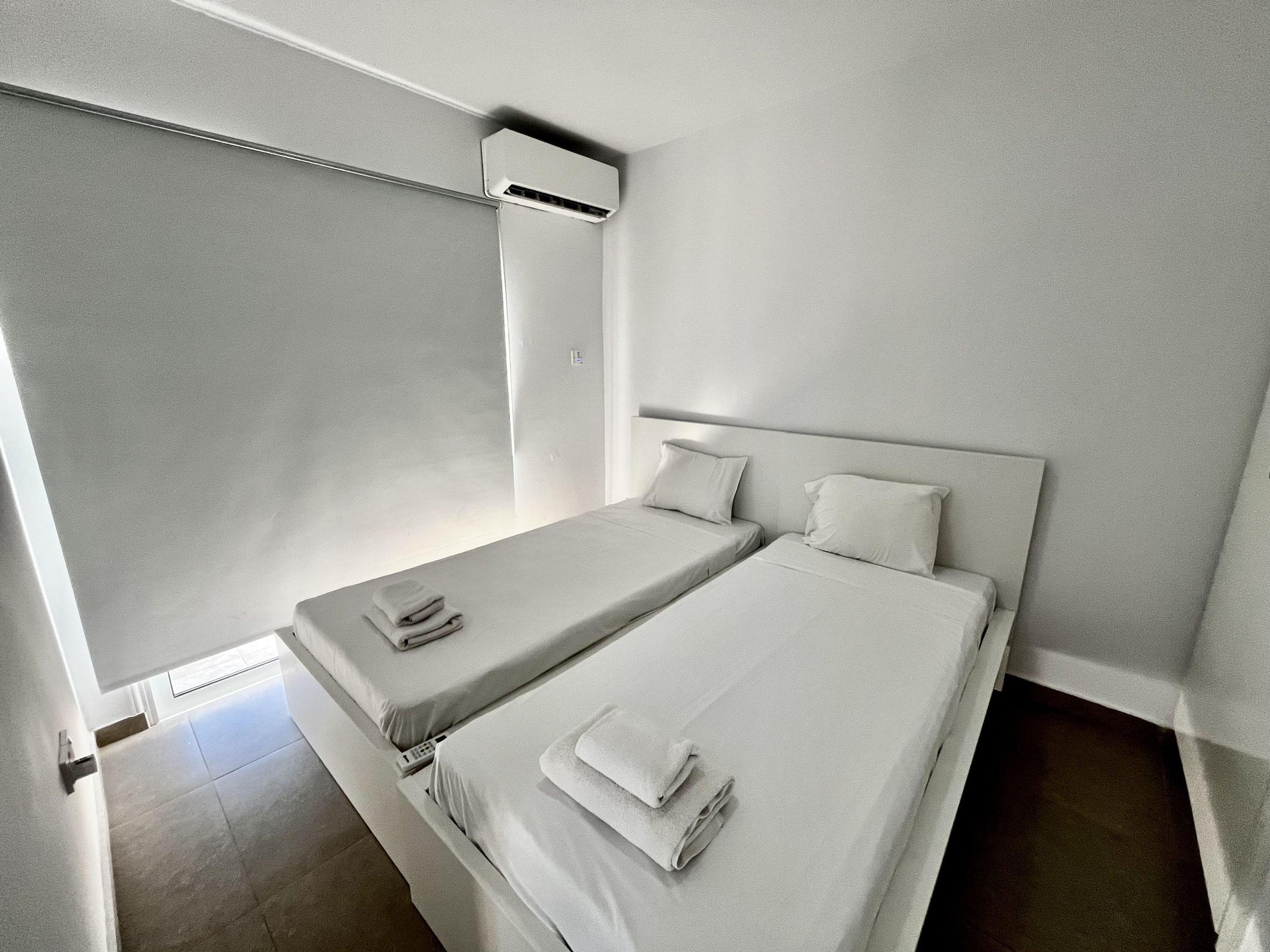 Een moderne hotelkamer met twee enkele bedden, een groot raam en een ingebouwde airconditioning.