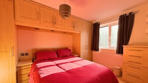 Ein Schlafzimmer mit einem Bett, einem Holzschrank und einem Fenster mit Vorhängen.