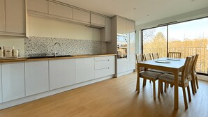 Eine moderne Küche mit weißen Schränken, einer Holz Arbeitsplatte und einem Essbereich mit Tisch und Stühlen.