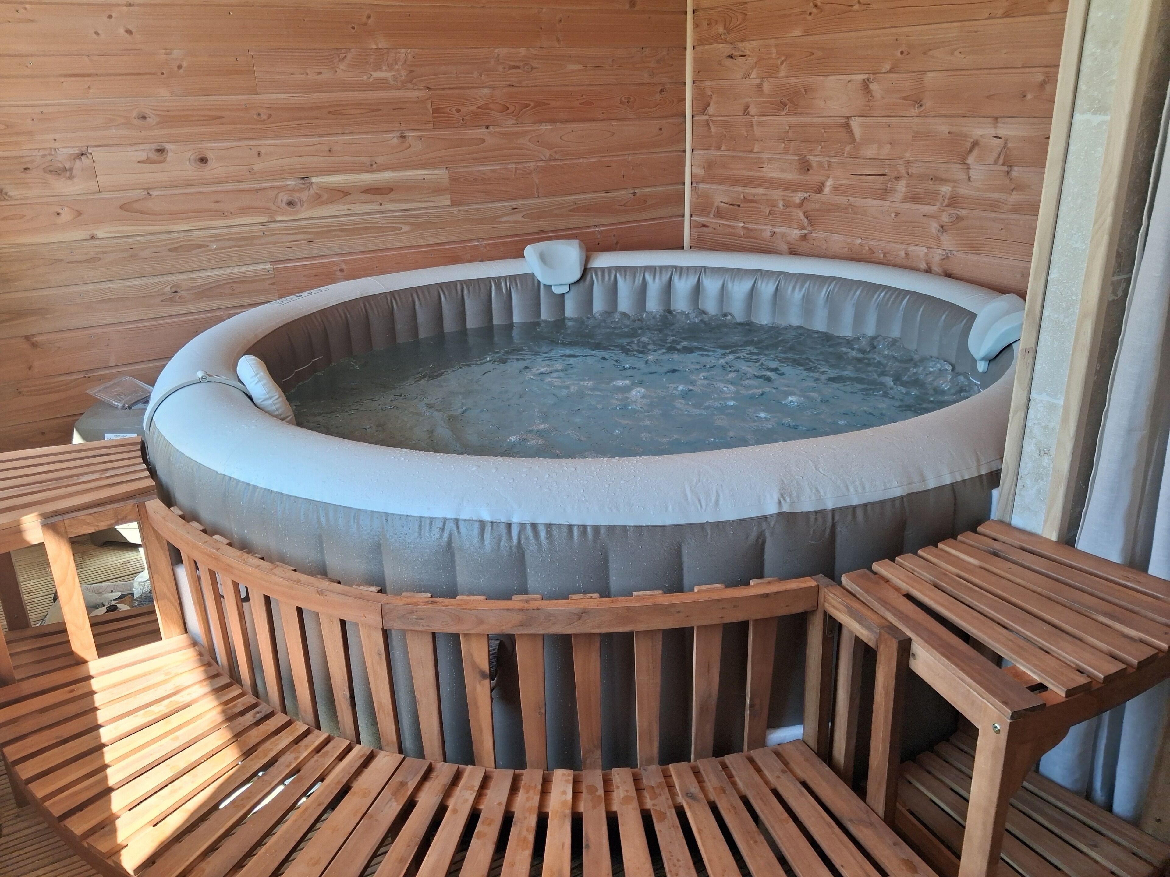 A wooden cabin with a hot tub and wooden furniture.