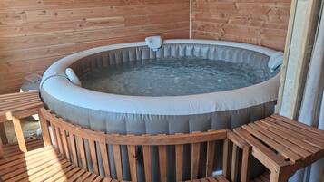 A wooden cabin with a hot tub and wooden furniture.