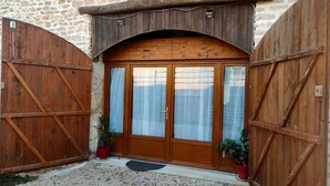 A rustic stone building with a wooden door and large wooden gates.