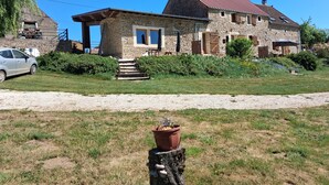 A stone house with a red roof, a gravel driveway, and a parked car.