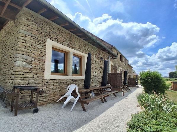 A stone building with a window, wooden benches, and a gravel path.
