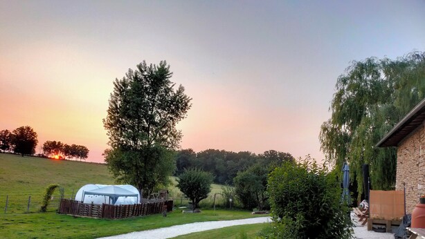 A campsite with a tent, a stone building, and a gravel path.