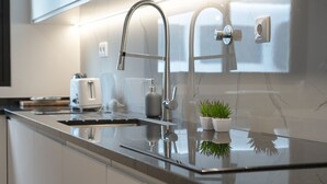 Una cocina moderna con un lavamanos de acero inoxidable, un grifo y una pequeña planta en maceta sobre la encimera.