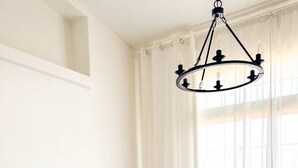 A room with a grey sofa, a patterned throw blanket, and a chandelier.