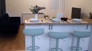 A kitchen with a central island, bar stools, and a dining table set for four.