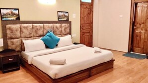 Ein Schlafzimmer mit hölzernem Kopfteil, einem Bett mit weißer Bettwäsche, einem blauen Kopfkissen und einem Nachttisch aus Holz.