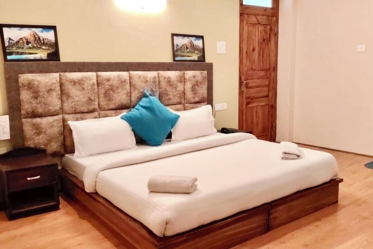 A bedroom with a wooden headboard, a bed with white bedding, a blue pillow, and a wooden nightstand.