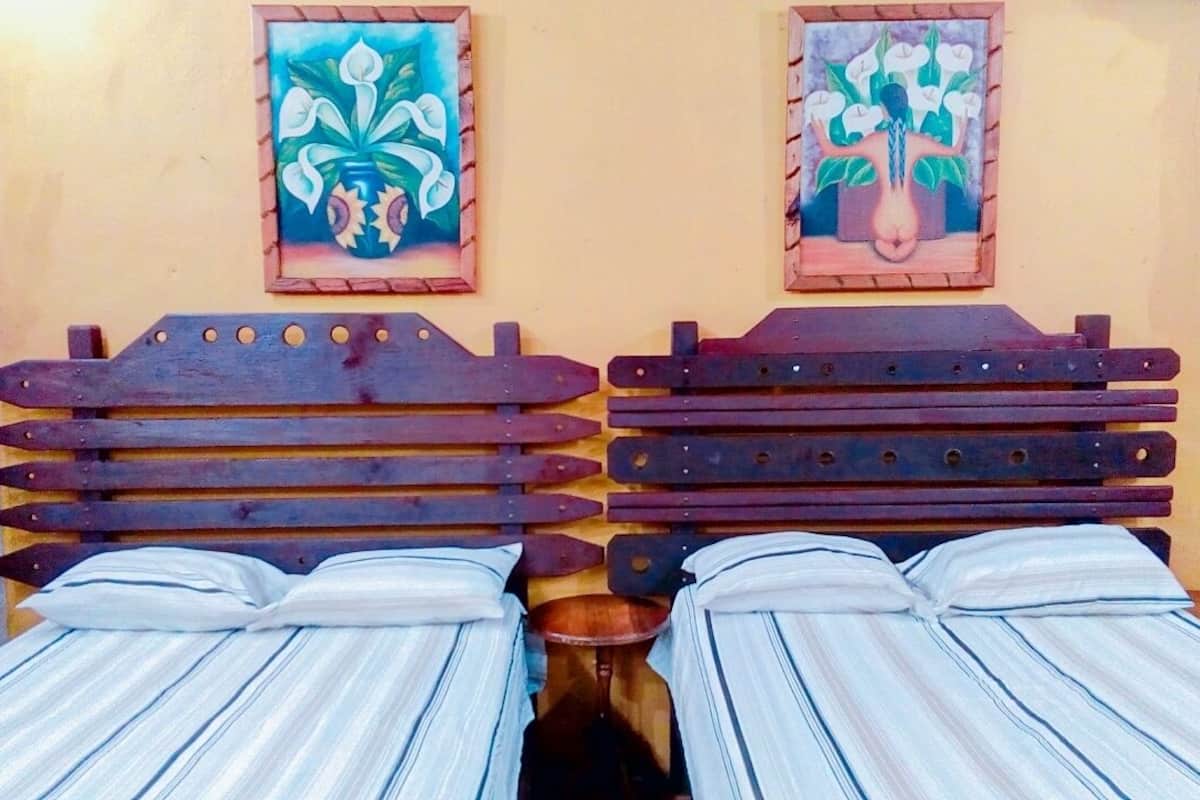 A room with two beds, each with striped bedding and wooden headboards.