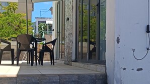 A set of stone steps leading to a covered outdoor area with a table and chairs, a wall-mounted light, and a potted plant. - Charming 2-bedroom villa with WiFi and AC in Grand Baie (Grand Baie)