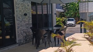 A modern outdoor pool area with a wooden deck, seating, and a covered patio. - Charming 2-bedroom villa with WiFi and AC in Grand Baie (Grand Baie)