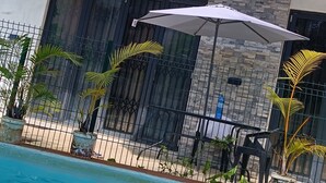 A modern two-story building with a swimming pool, outdoor seating, and potted plants. - Charming 2-bedroom villa with WiFi and AC in Grand Baie (Grand Baie)