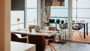 A modern dining area with a wooden table, brown leather chairs, and a view of the sea through large windows. - Hausboot am Grabendorfer See (Vetschau/Spreewald)