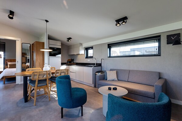 A modern living space with a dining area, kitchen, and seating area. - Docklodge Stay by the Water (Delfstrahuizen)