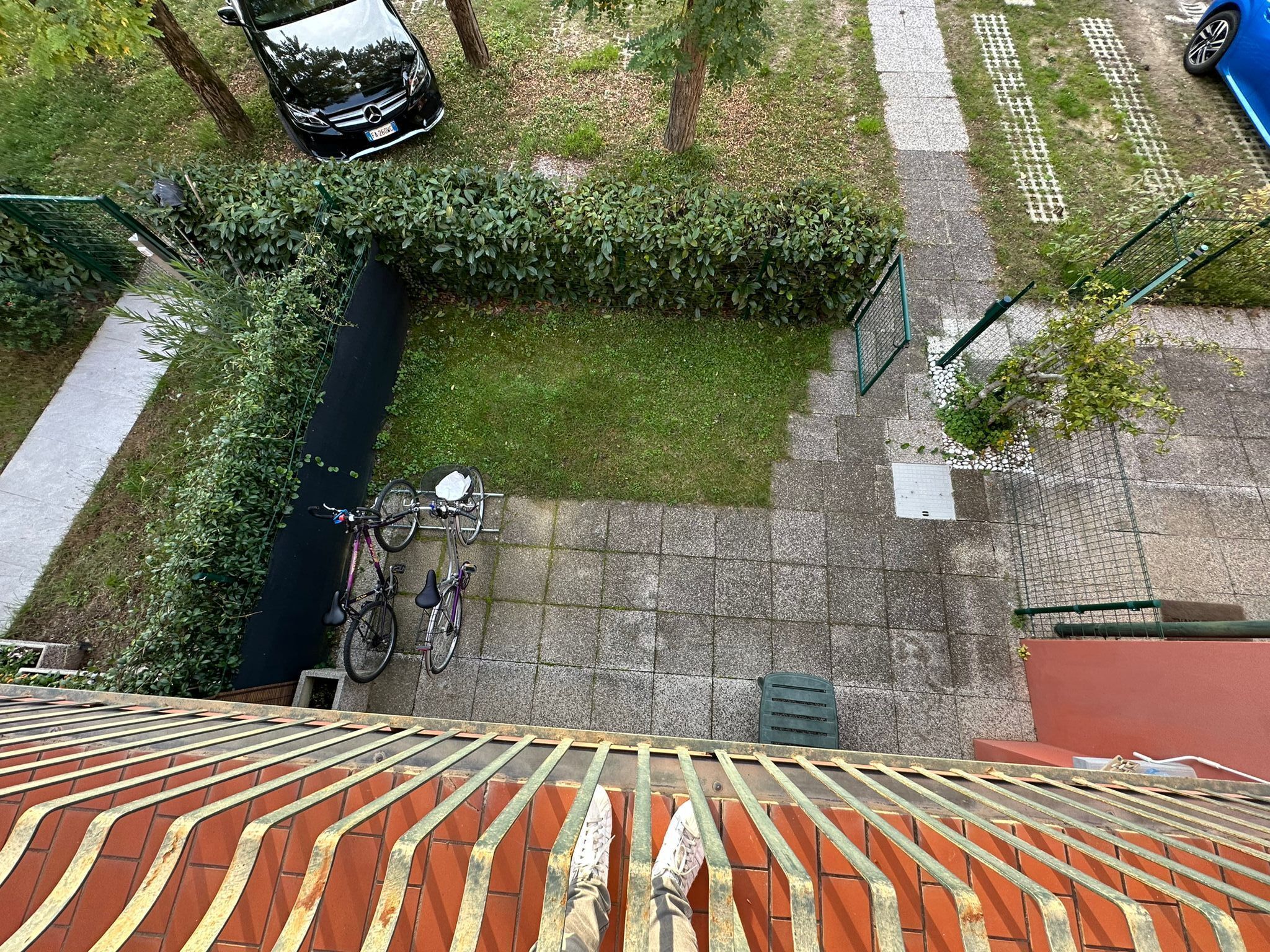 Une cour avec un vélo, une voiture et un bâtiment doté d’un toit rouge.