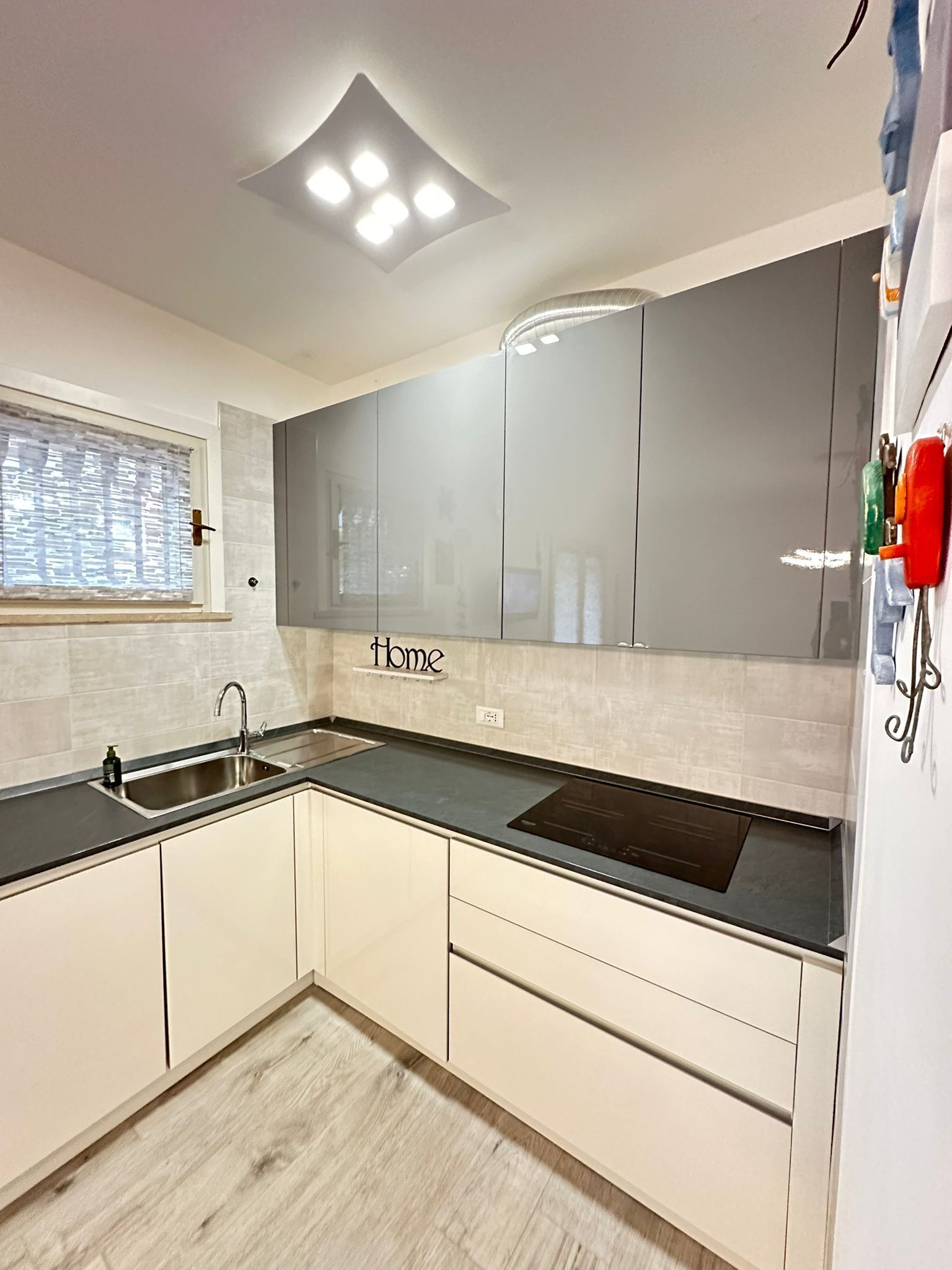 A modern kitchen with a sink, cabinets, and a window.