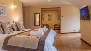 A hotel room with a large bed, a flat-screen TV mounted on the wall, and a wooden floor. - GRAN HOTEL AYSEN (Puerto Aysen)