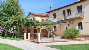 A two-story building with a balcony, a staircase, and a covered outdoor area.