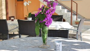 A table with a vase of purple flowers and a mug with a beach-themed message.