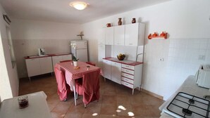 A compact kitchen with white cabinets, a red checkered table, and a gas stove.