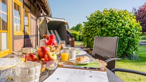 A breakfast setup with fruits, juice, and pastries on an outdoor table.