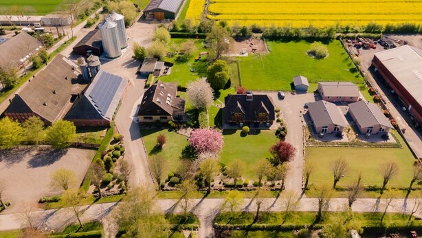 An aerial view of a rural area with agricultural fields, farm buildings, and a large silo.