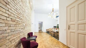 Ein Flur mit Backsteinwand, Holzboden, einem Essbereich mit Tisch und Stühlen sowie einer Tür.
